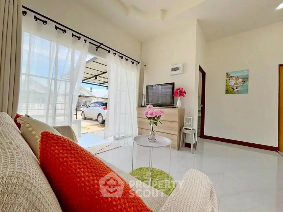 Bright and airy living room with modern decor and large windows opening to a carport.