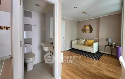 Cozy living room with adjacent compact bathroom, featuring modern decor and wooden flooring.