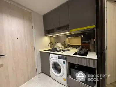 Compact modern kitchen with washing machine and microwave in sleek apartment