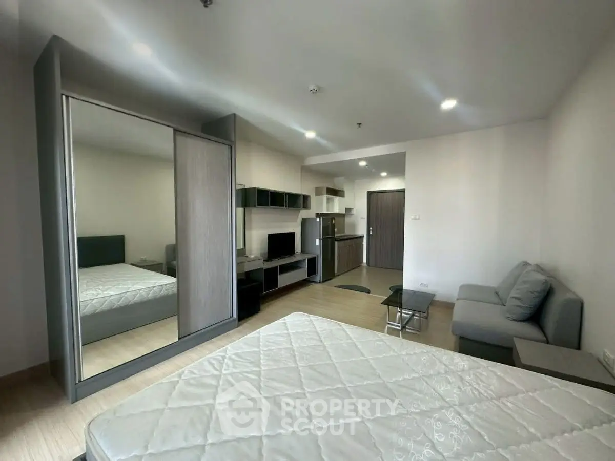 Modern studio apartment with sleek design, featuring a cozy living area, kitchenette, and mirrored wardrobe.