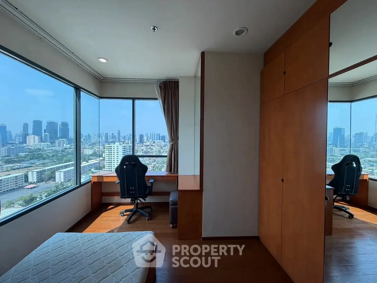 Spacious bedroom with city view, featuring a study desk and large windows for natural light.