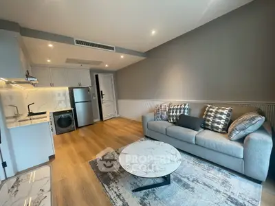 Modern living room with stylish decor, featuring a cozy sofa, marble coffee table, and compact kitchen area.