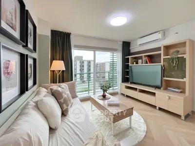Modern living room with cozy sofa, large TV, and balcony view in urban apartment.