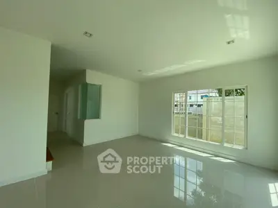 Spacious sunlit living room with large windows and glossy tiled floors in modern home.