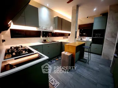 Modern kitchen with sleek cabinetry and island, featuring gas stove and stylish lighting.
