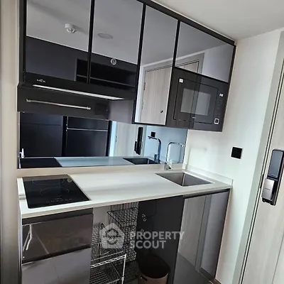 Modern compact kitchen with sleek cabinetry and built-in appliances in a stylish apartment.