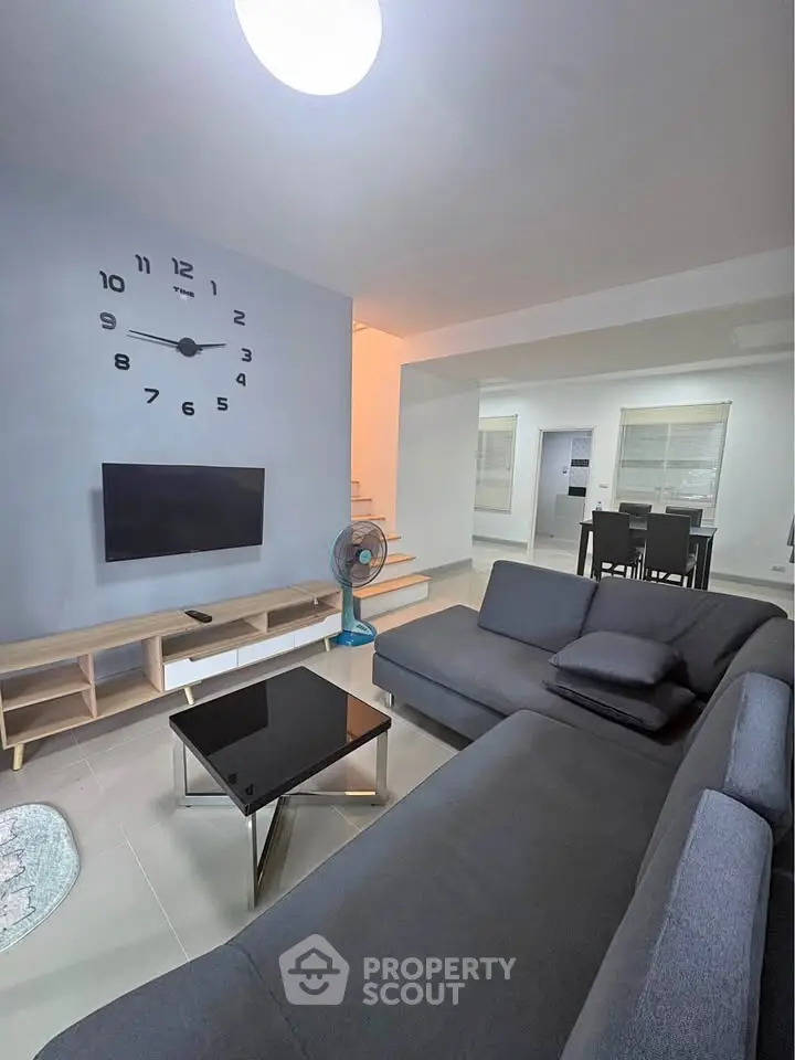 Modern living room with sleek furniture and wall-mounted TV, perfect for relaxation and entertainment.