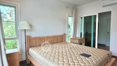 Spacious bedroom with wooden furniture and large windows offering natural light.