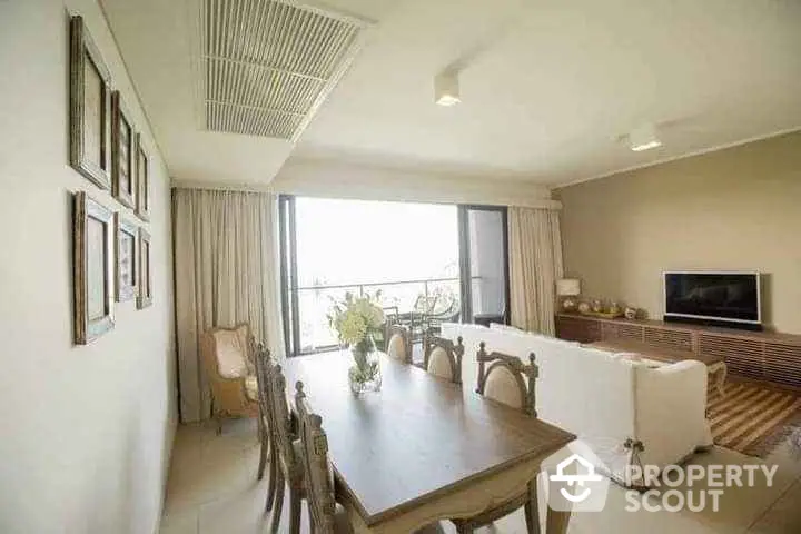 Elegant living room with dining area and large window offering natural light.