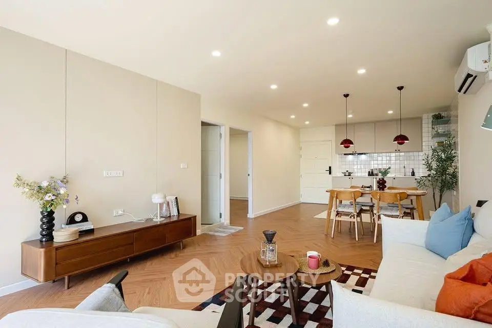 Spacious modern living room with open kitchen, stylish decor, and wooden flooring.