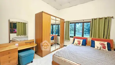 Spacious bedroom with large windows and stylish wooden furniture, offering a serene garden view.