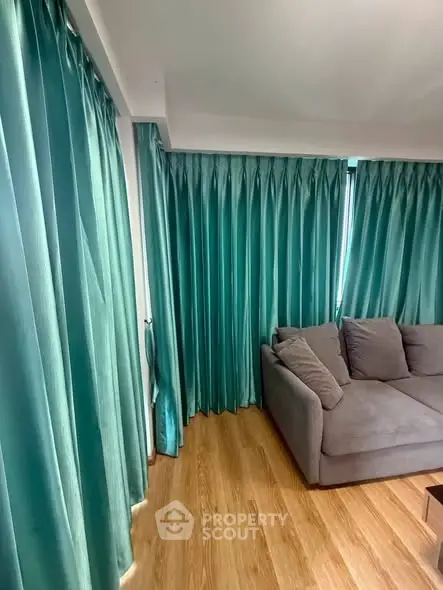 Cozy living room with teal curtains and a comfortable gray sofa