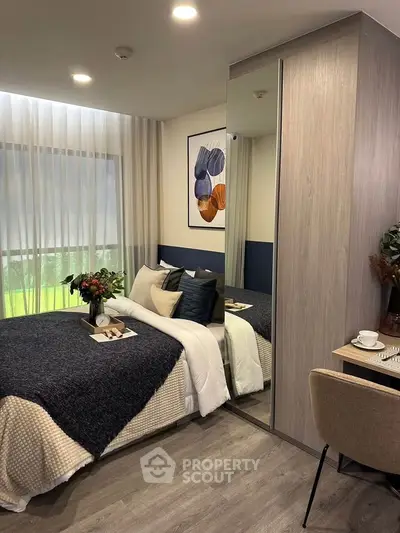 Modern bedroom with stylish decor and large window, featuring cozy bedding and elegant furnishings.