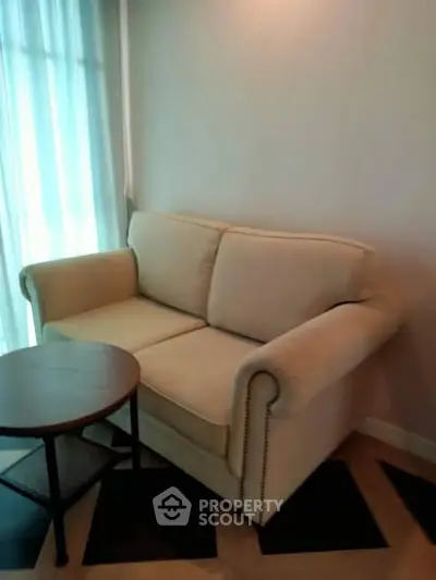 Cozy living room corner with a plush sofa and round wooden table.