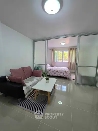 Modern apartment with cozy living room and bedroom separated by sliding glass doors.