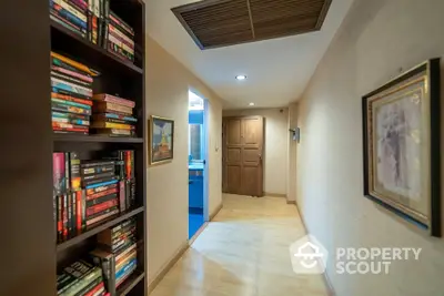 Cozy hallway with wooden flooring and built-in bookshelf, leading to a bathroom.