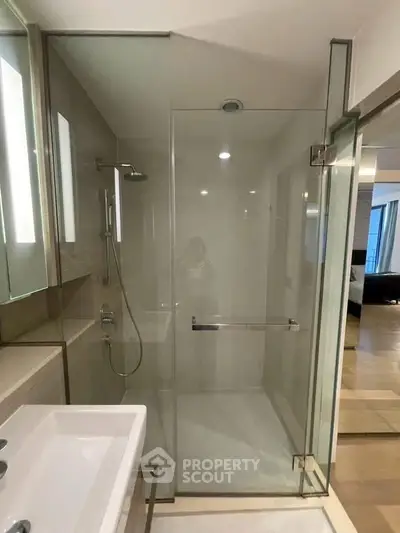 Modern bathroom with glass shower enclosure and sleek fixtures in a contemporary apartment.