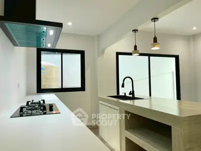 Modern kitchen with sleek design and gas stove, featuring a stylish island and pendant lighting.