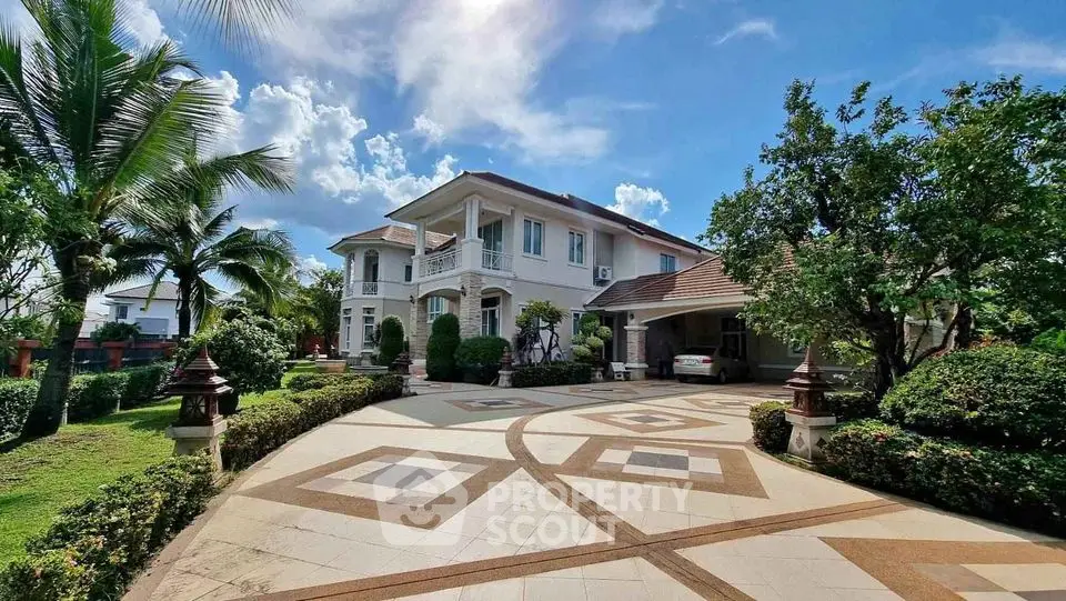 Luxurious villa with spacious driveway and lush garden under clear blue sky