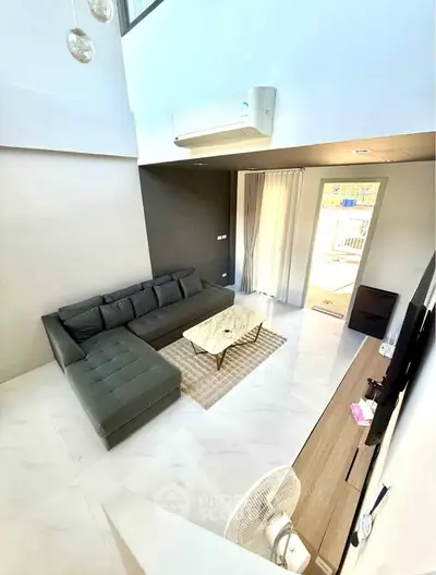 Spacious modern living room with high ceiling and natural light