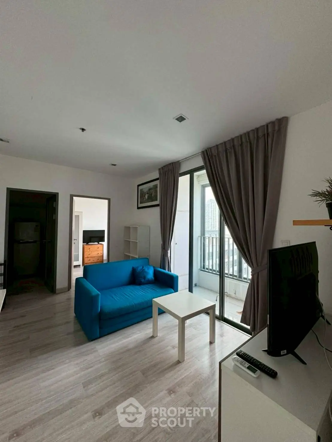 Modern living room with blue sofa, TV, and balcony access in a stylish apartment.