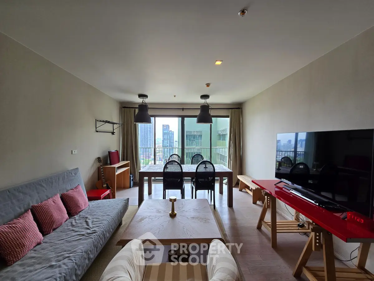 Spacious living room with modern decor and city view, featuring a large sofa and dining area.