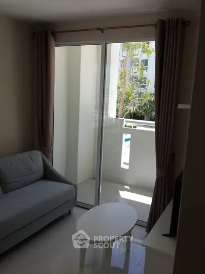 Cozy living room with sliding glass doors leading to a small balcony, offering a serene view.
