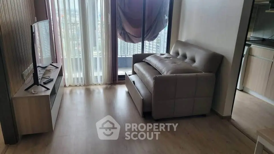 Modern living room with large window and stylish furniture in a high-rise apartment.