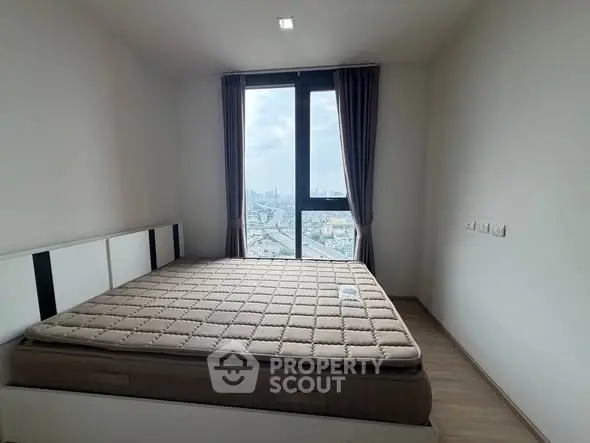 Modern bedroom with large window offering stunning city view.