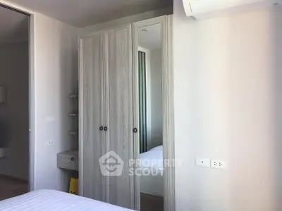 Modern bedroom with mirrored wardrobe and air conditioning unit.