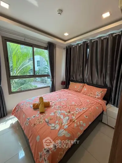 Cozy bedroom with floral bedding and large window view of lush greenery.