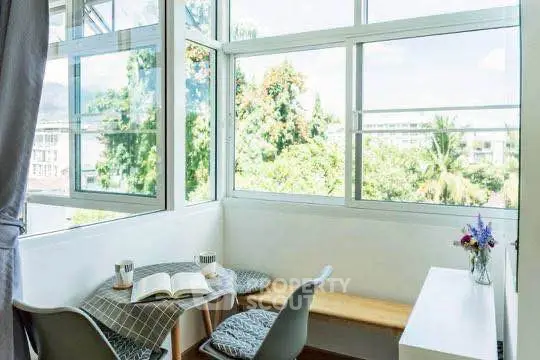 Bright corner nook with large windows and cozy seating, perfect for reading and relaxation.