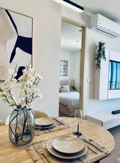 Modern dining area with elegant table setting and view into cozy bedroom