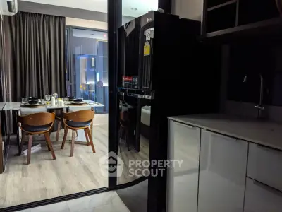 Modern kitchen with sleek black fridge and dining area with elegant table setting.