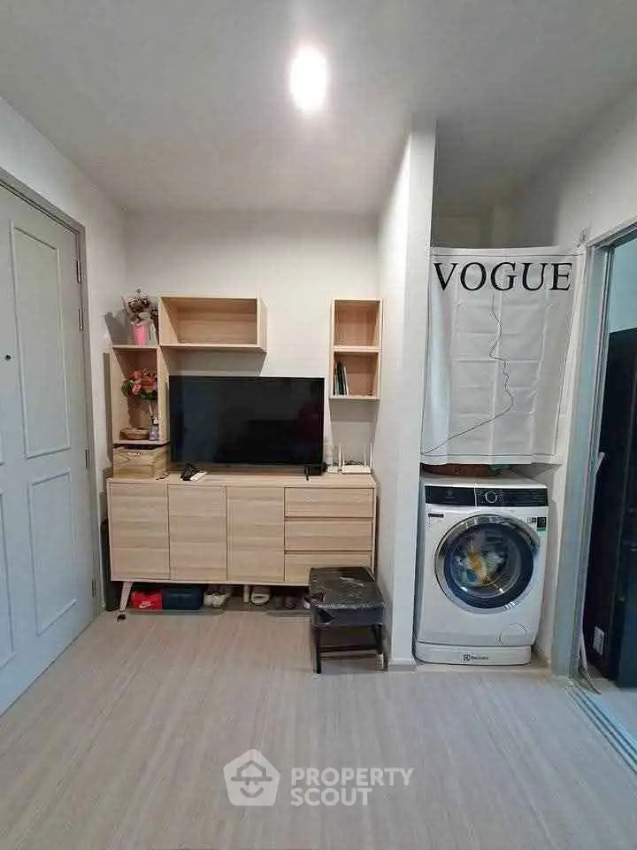 Modern living room with stylish TV unit and washing machine in compact space.