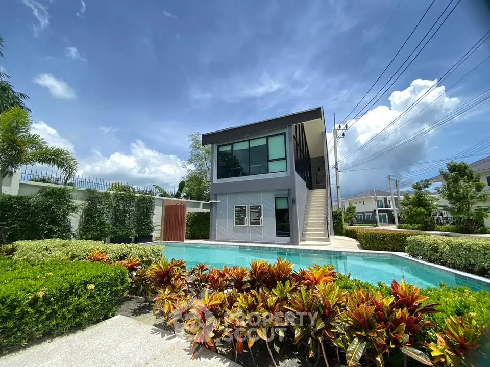 Modern two-story house with pool and lush garden in a serene neighborhood.