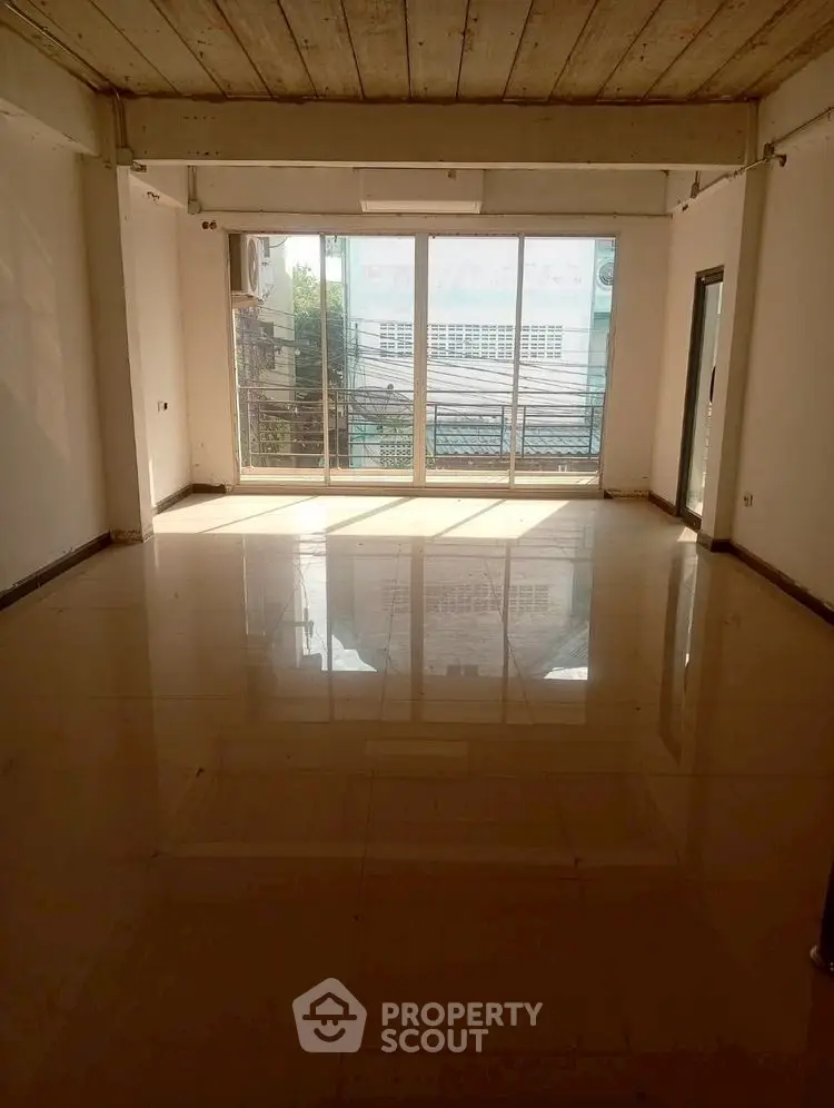 Spacious sunlit room with large windows and glossy tiled floor, ideal for versatile living space.