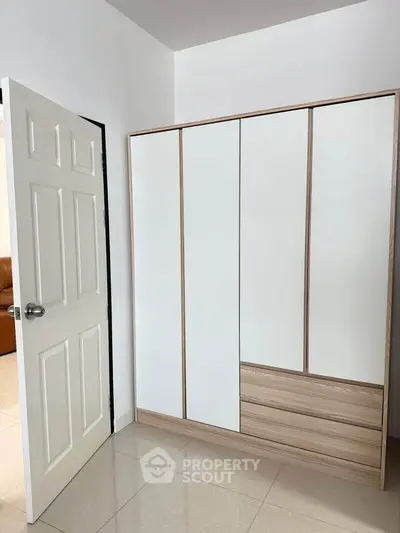 Modern minimalist wardrobe in a bright room with open door and tiled floor.
