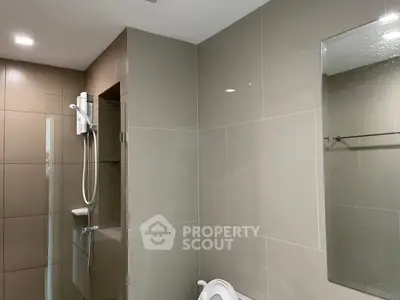 Modern bathroom with sleek tiles and shower unit, perfect for contemporary living.