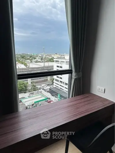 Modern study area with city view from high-rise window, featuring sleek desk and chair.
