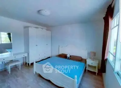 Spacious bedroom with elegant white furniture and large window for natural light.