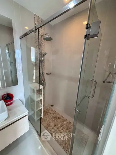 Modern bathroom with glass shower enclosure and stylish vanity unit.