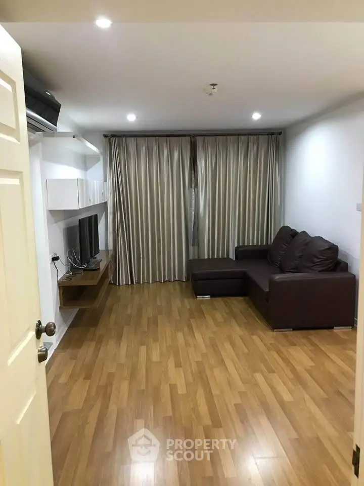 Spacious living room with modern decor and wooden flooring, featuring a comfortable sofa and entertainment unit.