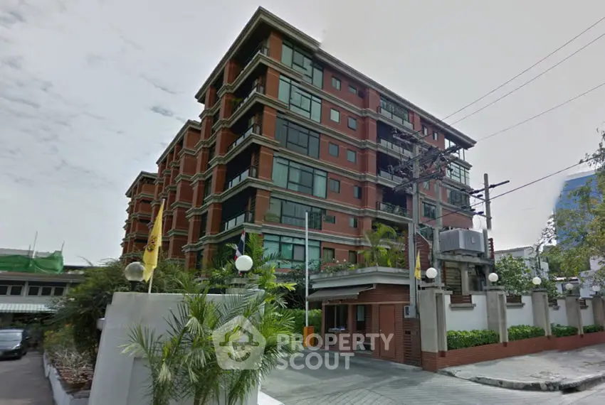 Modern multi-story residential building with large windows and lush greenery.