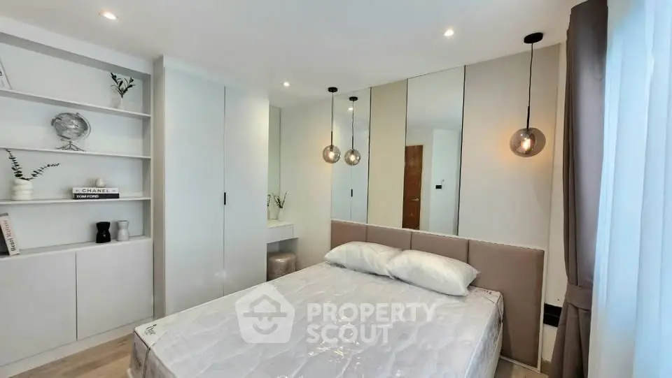 Modern bedroom with elegant decor, built-in storage, and stylish lighting in a cozy apartment.