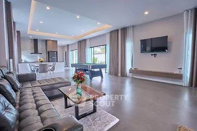 Spacious modern living room with open kitchen and pool table, perfect for entertaining.