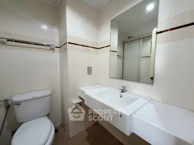 Modern bathroom with sleek white fixtures and large mirror