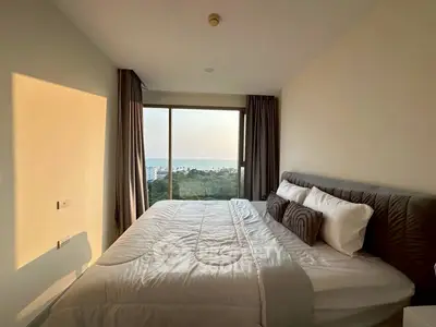 Cozy bedroom with a stunning view of the ocean and lush greenery.
