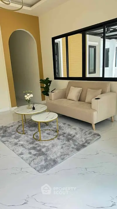 Stylish living room with modern beige sofa, elegant coffee tables, and chic decor in a contemporary home.