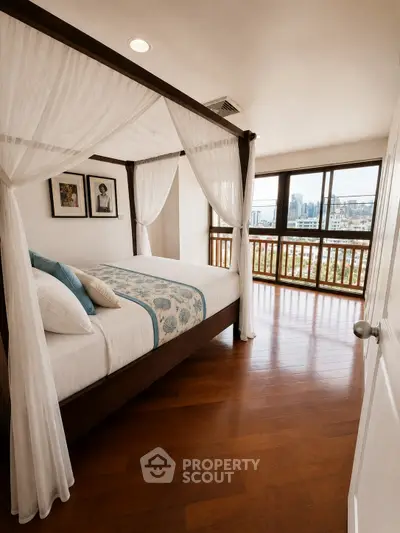 Luxurious bedroom with canopy bed and stunning city view from large windows.